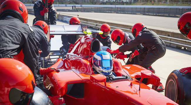 Tripulação do poço substituindo pneus na fórmula um carro de corrida na pista de pit — Fotografia de Stock
