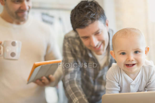Portrait cute baby son with male gay parents using digital tablet — Stock Photo