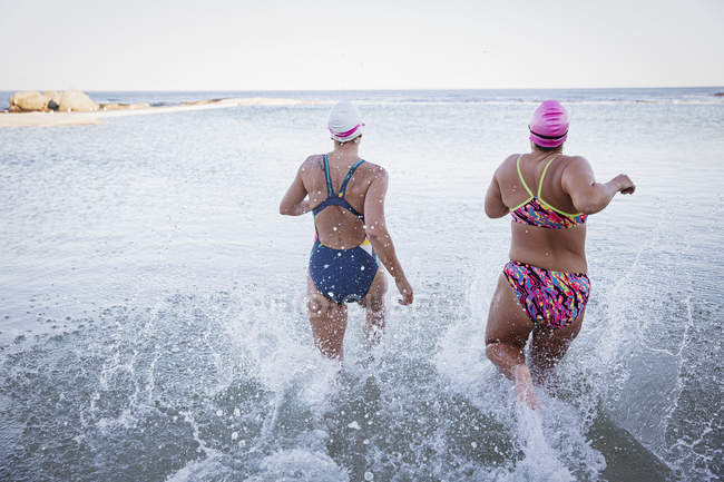 Rückansicht der aktiven Schwimmerinnen, die im Freien am Meer laufen — Stockfoto