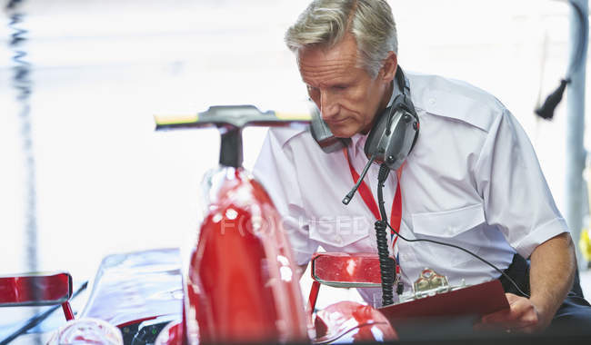 Manager with clipboard next to formula one race car — Stock Photo