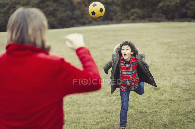 Father cheering for playful son running in park — Stock Photo