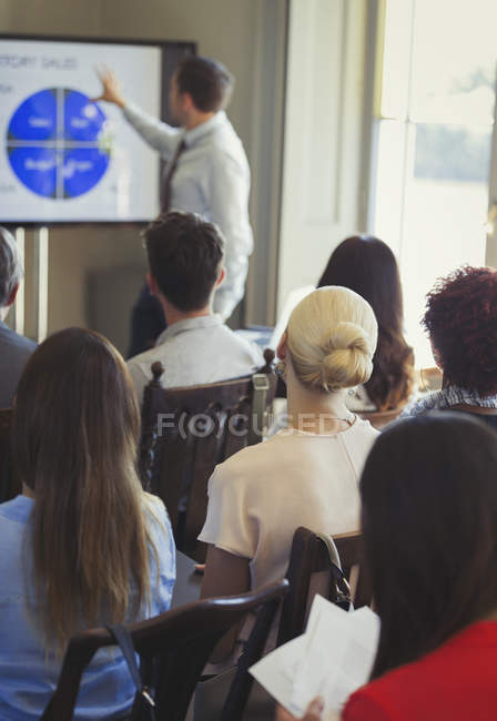 Business people in audience watching businessman leading conference presentation at television screen — Stock Photo