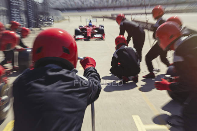 Pit crew listo para acercarse a la fórmula de un piloto de carreras de coches en pit lane - foto de stock
