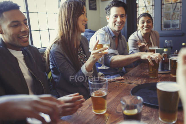 Freunde trinken Bier und Wein und unterhalten sich am Tisch in der Bar — Stockfoto