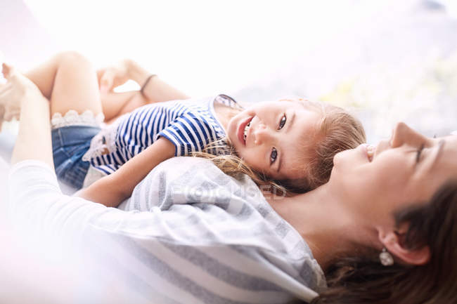 Portrait smiling daughter laying on top of mother — Stock Photo