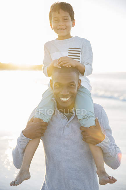 Retrato del padre llevando a su hijo en hombros y sonriendo - foto de stock