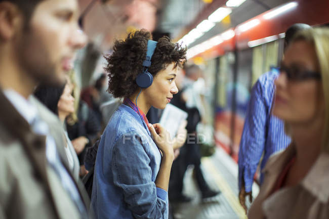 Mulher ouvindo fones de ouvido na estação de trem — Fotografia de Stock