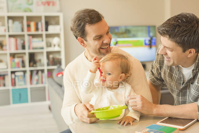 Male gay parents feeding baby son — Stock Photo