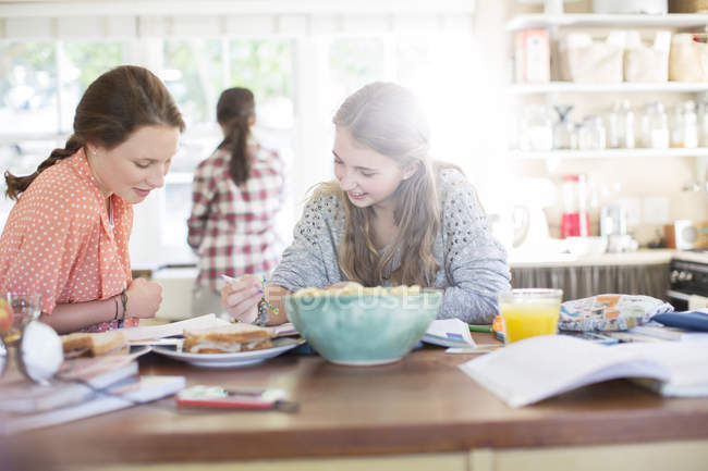 Девочки-подростки учатся за столом на кухне — стоковое фото