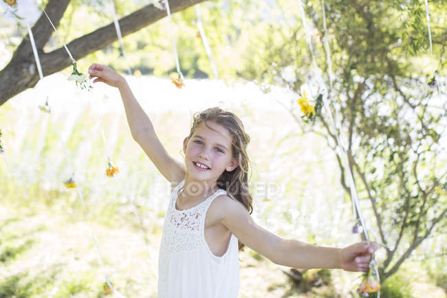 Damigella d'onore sorridente che gioca con decorazioni nel giardino domestico durante il ricevimento di nozze — Foto stock