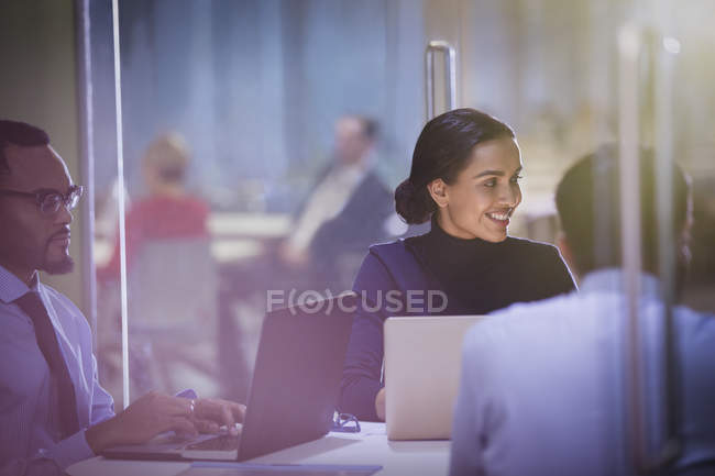 Улыбающаяся деловая женщина за ноутбуком слушает в конференц-зале — стоковое фото
