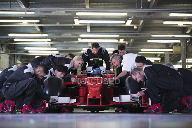 Equipe de poço preparando fórmula um carro de corrida e motorista na garagem de reparação — Fotografia de Stock