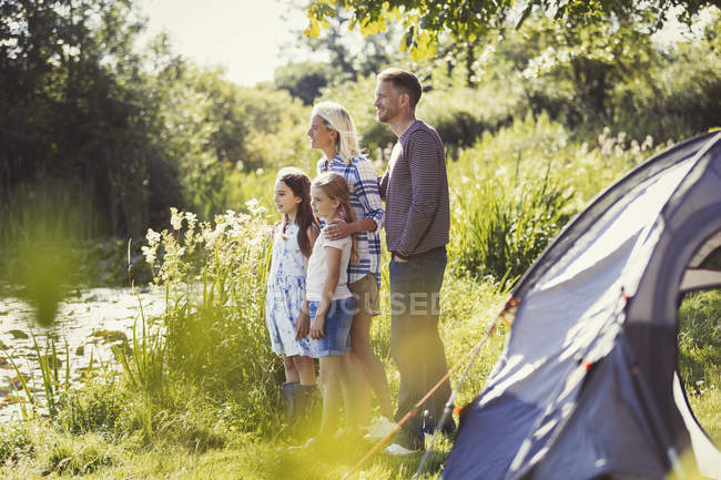 Family at sunny campsite lakeside looking away — Stock Photo