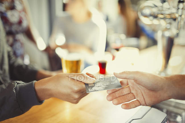 Frau bezahlt Barkeeper an Bar mit Kreditkarte — Stockfoto