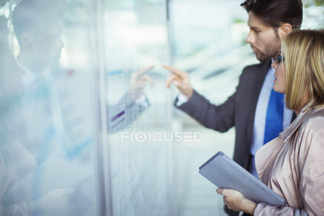 Business people reading transportation schedule at station — Stock Photo