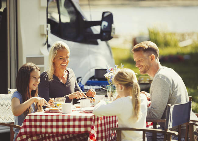 Family enjoying breakfast at table outside sunny motor home — Stock Photo