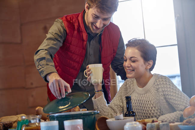 Couple cooking and drinking at cabin table — Stock Photo