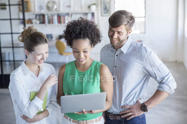 Three young people looking at digital tablet in studio — Stock Photo