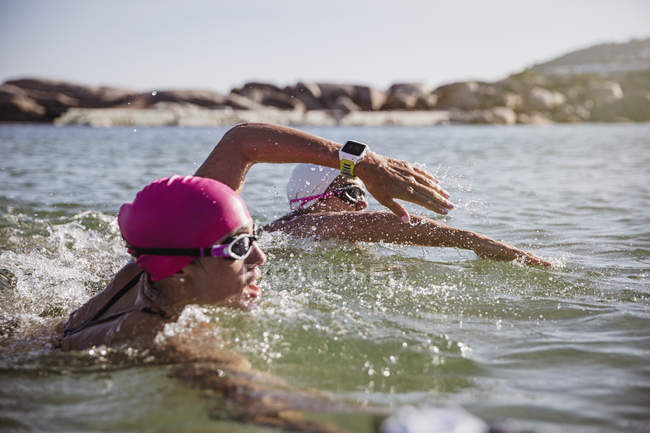Жіночий плавець з відкритою водою з розумним годинником, який плаває в сонячному океані — стокове фото