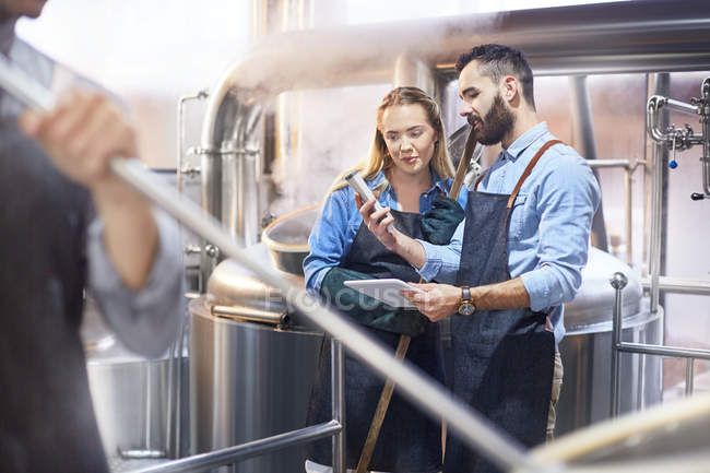 Coffee roasters with digital tablet checking gauge at tank — Stock Photo