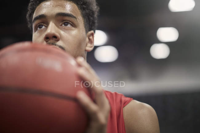 Primer plano enfocado joven jugador de baloncesto masculino celebración de baloncesto - foto de stock