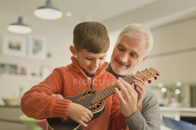 Отец учит сына играть на укулеле — стоковое фото
