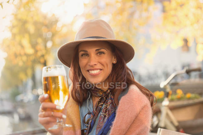 Retrato sorrindo jovem mulher brindando copo de cerveja no outono café calçada — Fotografia de Stock