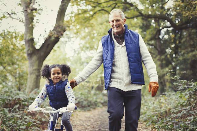 Grandfather and granddaughter bike riding in autumn park — Stock Photo