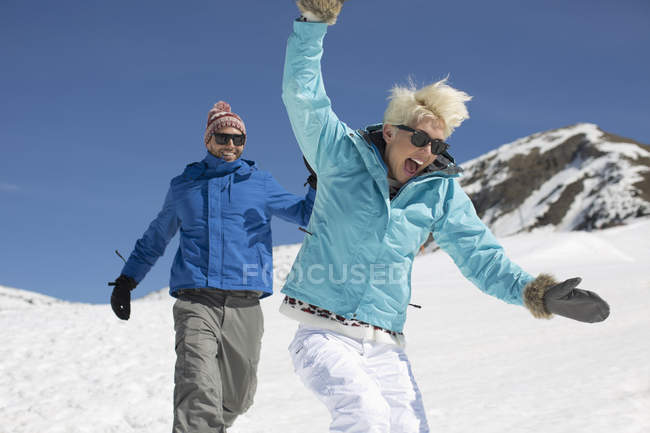 Casal exuberante jogando na neve — Fotografia de Stock