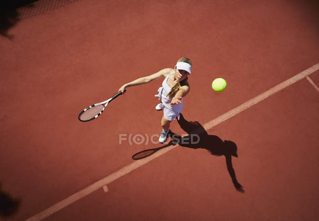 Junge Tennisspielerin spielt Tennis, serviert den Ball auf sonnigem Sandplatz — Stockfoto