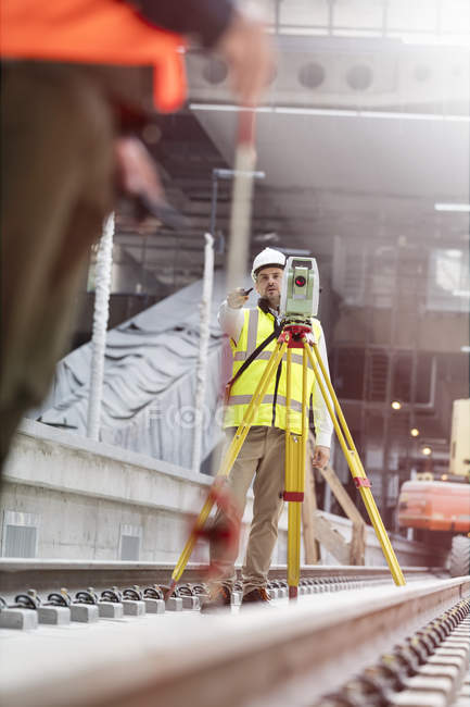 Чоловік-інженер, який використовує теодоліт на коліях на будівельному майданчику — стокове фото