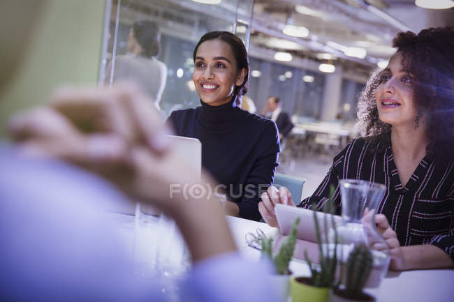 Lächelnde Geschäftsfrauen hören im Konferenzraum zu — Stockfoto