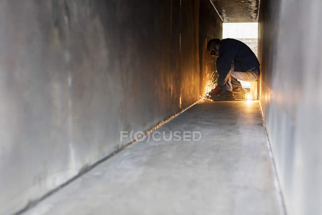 Welder using welding torch in steel tunnel — Stock Photo