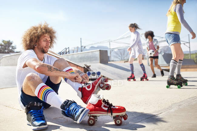 Чоловік одягає роликові ковзани в сонячний скейт-парк — стокове фото
