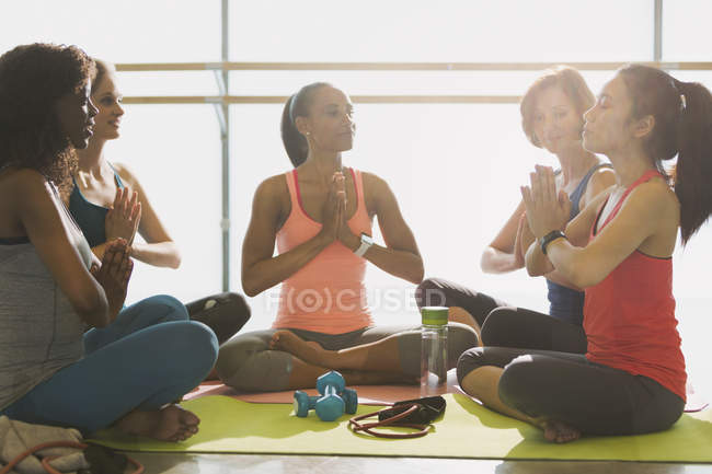 Serene women meditating in yoga class gym studio — Stock Photo