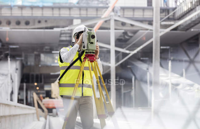 Инженер-мужчина, использующий теодолит на строительной площадке — стоковое фото