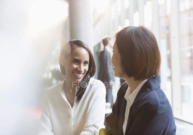 Усміхнені бізнес-леді розмовляють разом в сучасному офісі — стокове фото