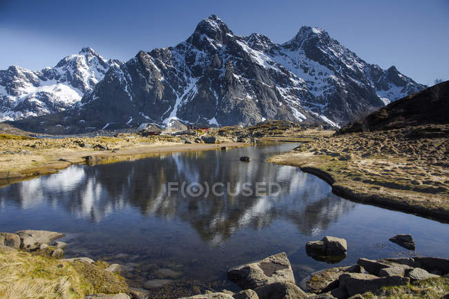 Snow on remote, sunny, craggy mountains above water, Maervoll, Lofoten, Norway — Stock Photo