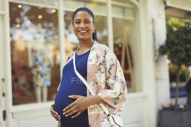 Porträt lächelnde, selbstbewusste Schwangere vor Schaufenster — Stockfoto