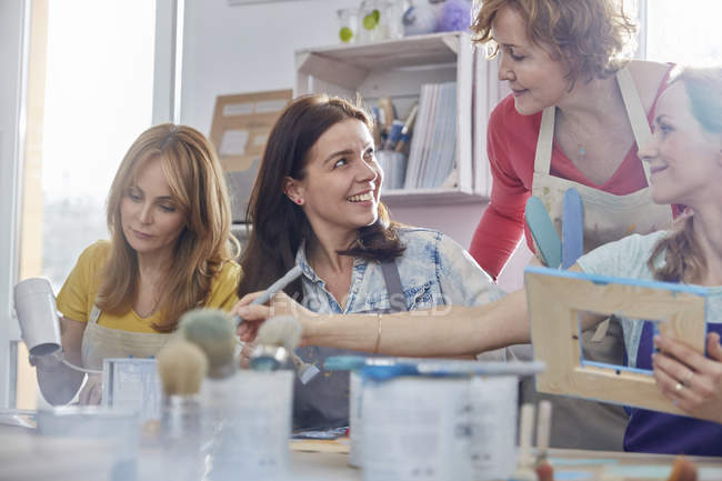 Instructrice aidant les élèves à peindre des cadres dans un atelier de classe d'art — Photo de stock