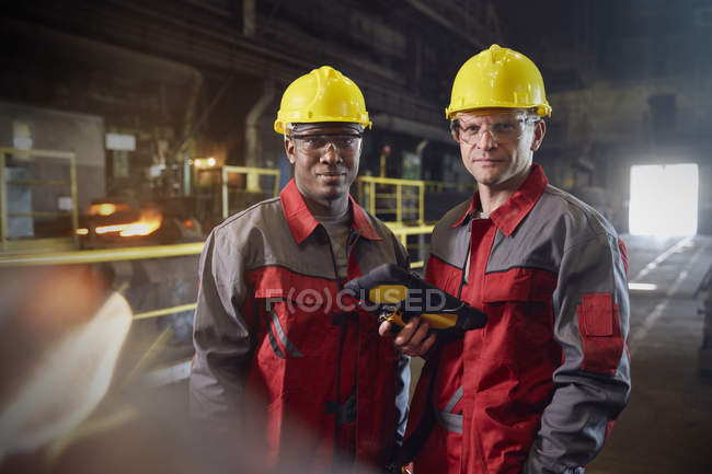 Портрет уверенных сталеваров с цифровым планшетом на сталелитейном заводе — стоковое фото