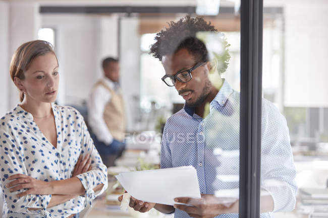 Homme d'affaires et femme d'affaires discutant de la paperasserie au bureau — Photo de stock