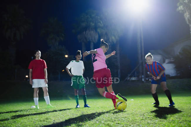 Jeunes joueuses de soccer pratiquant sur le terrain la nuit — Photo de stock