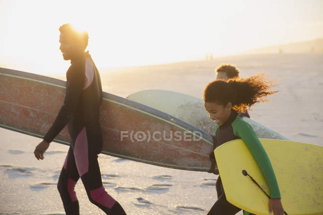 Famille portant des planches de surf et des planches de boogie sur la plage ensoleillée d'été — Photo de stock