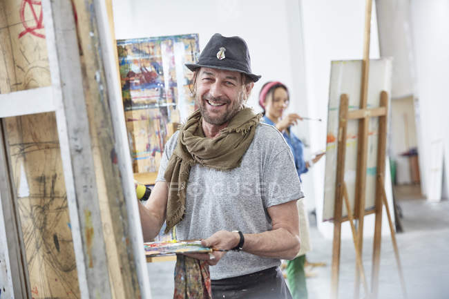 Retrato sorrindo artista masculino pintura no cavalete em estúdio de classe de arte — Fotografia de Stock