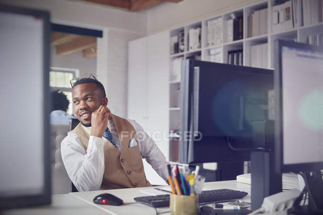 Улыбающийся бизнесмен, работающий за компьютером в офисе — стоковое фото