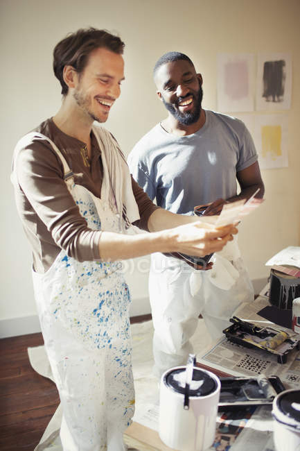 Gay couple viewing paint swatches, painting living room — Stock Photo