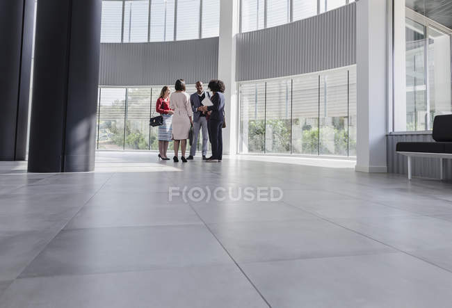 Business people talking in modern office lobby — Stock Photo
