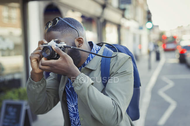 Молодий чоловік турист фотографує з камерою на вулиці — стокове фото