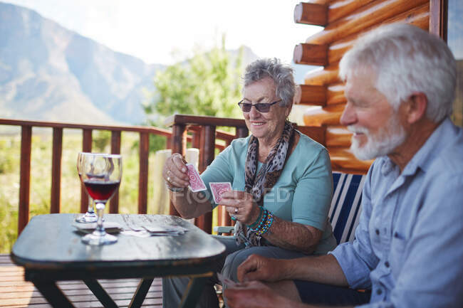 Coppia anziana attiva bere vino e giocare a carte sul balcone cabina — Foto stock
